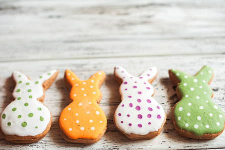 Multicolored gingerbread cookies on white wooden textural background. Homemade gingerbread easter...