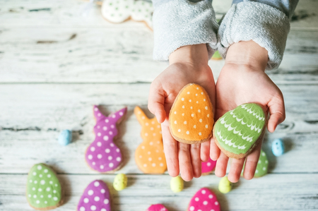 Gingerbread cookies on white background. Kids hands holding homemade gingerbread cookies, easter concept postcardsの写真素材