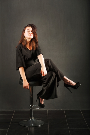 Black leather jacket on a dark key. Young woman in studio in black suitの写真素材