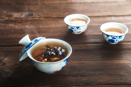Green wooden background with copy space. Tea flower in a porcelain cup and steamの写真素材