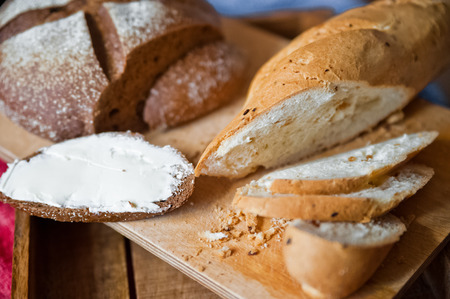 Sliced baguette and round rye black bread. Sandwich with bread, butter and dill. White loaf and rye breadの写真素材
