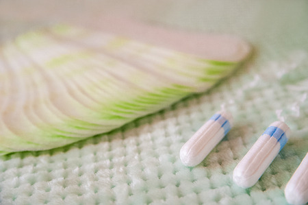 Hygienic tampons and pads on a textured turquoise background. Means of female intimate hygiene close-up and copy space.の写真素材