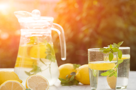 Homemade refreshing lemonade in decanter close-up and copy space. Lemonade from lemons, mint, ice.の写真素材