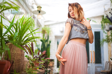 Beautiful girl in pink dress Woman in yoga asanas in a greenhouse with flowers.の写真素材
