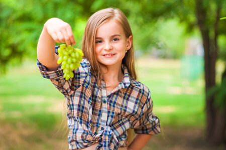 Girl holding a bunch of green grapes close-up. Concept of harvesting a girl and a girl copy space.の写真素材