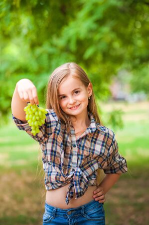 Girl holding a bunch of green grapes close-up. Concept of harvesting a girl and a girl copy space.の写真素材