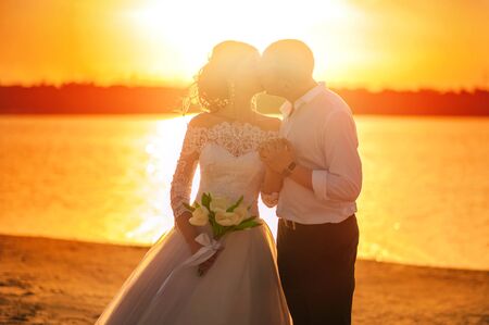 Romantic wedding couple at sunset The bride and groom on the beach at sunset in summer.の写真素材