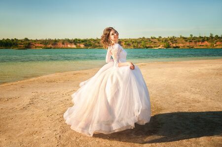 Romantic wedding couple on the shore. The bride runs along the shoreline against the backdrop of a lake or sea.の写真素材