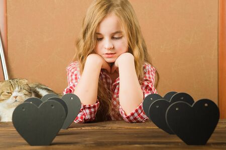 The girl writes a love message on Valentine's Day. Baby with heart close-up and copy space. Children's hands write a love message on Valentine's Day. Stamps with hearts and love on the letter closeupの写真素材