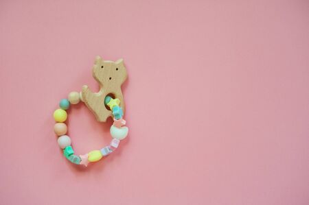 Wooden baby teether with beads. Minimalistic flat lay with a wooden toys cat an isolated pink...