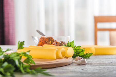 Cannelloni on a plate with meat and tomato sauce. Italian paste. Crude cannelloni on a kitchen table. Top view. Canneloni (Pasta with cheese and vegetable filling) with spinach and feta cheese with toの写真素材