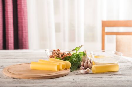 Cannelloni on a plate with meat and tomato sauce. Italian paste. Crude cannelloni on a kitchen table. Top view. Canneloni (Pasta with cheese and vegetable filling) with spinach and feta cheese with toの写真素材