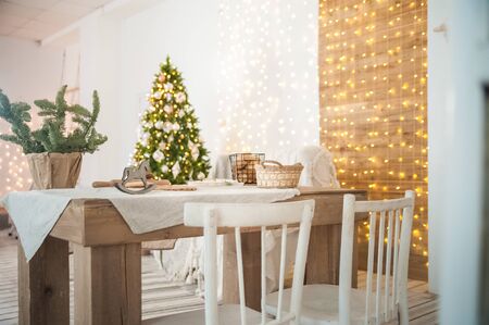 Rustic kitchen and living room interior decorated for Christmas. New Year's interior of the Scandinavian style. Textural light room of a farmer's house with a Christmas tree and a garland. Backgroundの写真素材