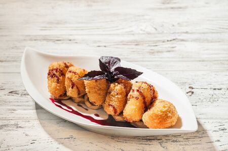 Camembert in a restaurant close-up. Fried breaded camembert with berry sauce on a white plate and...