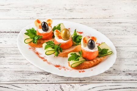 Seafood rolls in a restaurant close-up. Salmon rolls with cheese and olive on toast on a white plate and copy space.の写真素材
