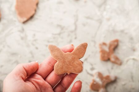 The process of making gingerbread. Hands cut gingerbread cookies closeup. Easter gingerbread dough, flour, rolling pin and copy space.の写真素材