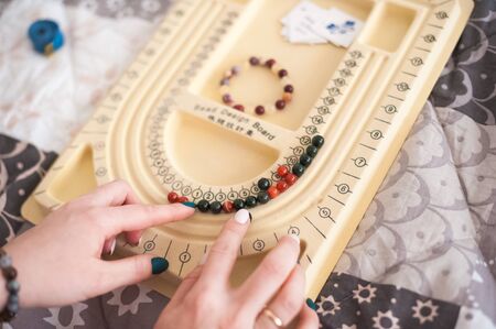 Bracelets made of natural stones. Girl creates handmade jewelry close-up. The mystic of amulets,...
