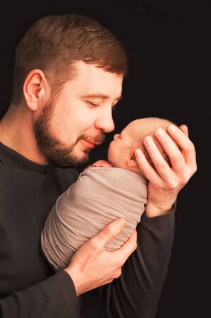 Communication father and son. Holiday concept Father's Day. Father with a beard holds a newborn in...