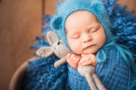 Little newborn baby with a hare closeup and copy space. Newborn photo in a blue diaperの写真素材