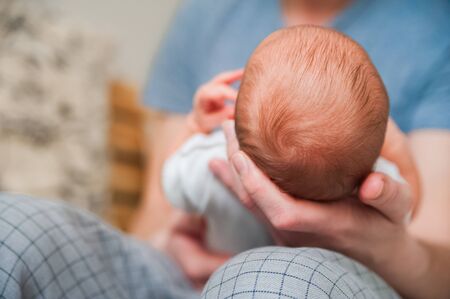 Head of a newborn close up. The father holds in the hands of the infant and copy space. Baby care...