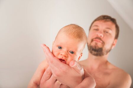 Newborn on the bed with his father close-up. The concept of the relationship of children and parents...
