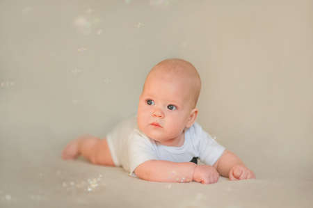 Newborn baby in white bodysuit and tie. Baby and copy space. Small child care, bathing, grimacing.