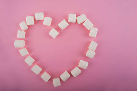 Heart shaped marshmallows on a pink background close up and copy space. Marshmallow heart top view on a pink background.の写真素材
