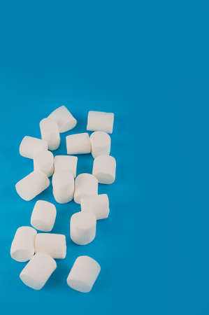 Marshmallows in the shape of a heart on a blue background close-up and copy space. Marshmallow pattern top view on a blue background.の写真素材