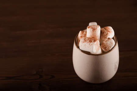 Marshmallows in a mug on a dark background close-up and copy space. Marshmallow in a cup with cocoa...