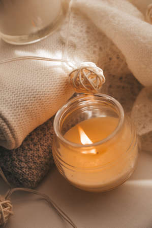 A cozy and warm hygge concept with white sweaters, candles, a cup, a garland on the windowsill. Autumn trendsの写真素材