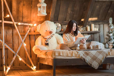 A woman is quarantined at home during the New Years. Girl at home in Hugge interior for Christmas in the bedroom.の写真素材