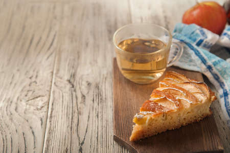 Homemade apple pie on a white wooden background near the window close-up and copy space. Charlotte in the morning on the table.の写真素材