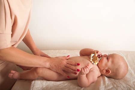 Massage the newborn close up. Female hands massage baby, newborn care concept, massage of abdominal colic, teething.の写真素材