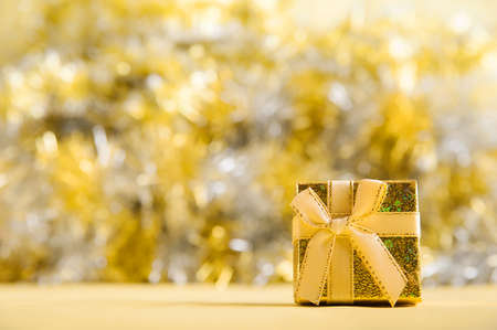 Beautiful yellow box with a bow on a yellow background. Gift in gold texture. Shopping concept,...