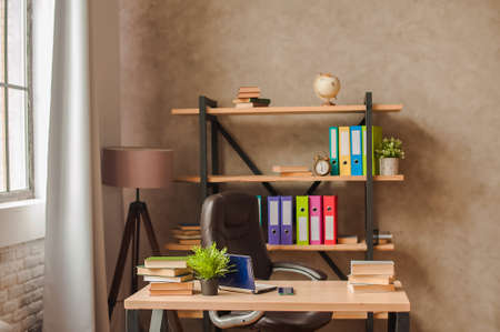 Workplace at home. Rack with folders and table with laptop close-up and copy space. Working at home concept.の写真素材