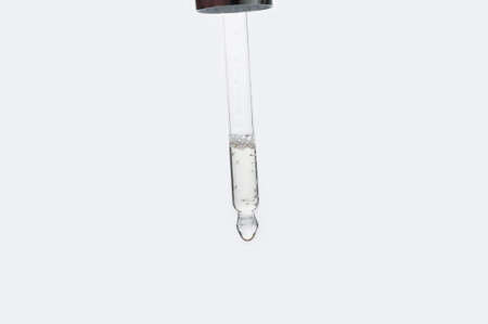 Pipette with essential oil on blurred flower background