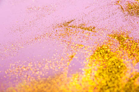 Gold sparkles on pink background and copy space. Trendy background for inscription with yellow confetti.の写真素材