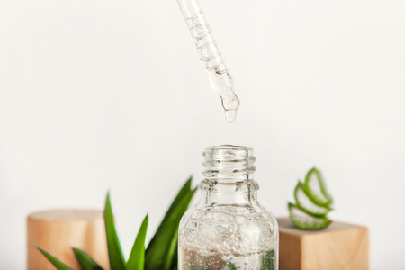 Serum with pipette close-up, skincare concept. Aloe vera out of focus on background of cosmetics.の写真素材