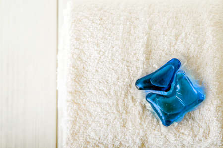 Blue laundry capsule and stack of terry towels. Concentrated detergent and cleanliness.の写真素材