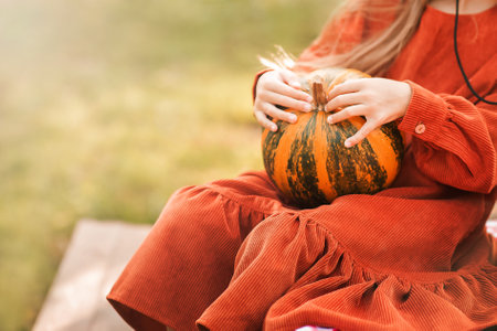 Close-up of pumpkin in hands of girl. Autumn and harvest concept, Thanksgiving.の写真素材
