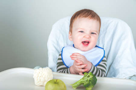 Handsome boy with spoon smiles on blue background. oncept of healthy eating and first feeding of...