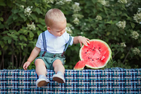 Yummy watermelon and little funny toddler in nature. First feeding of child with watermelon...の写真素材