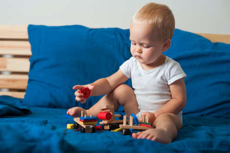 Toddler boy on blue bed with with wooden constructor blocks before sleep close-up and copy space...の写真素材