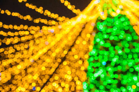 Christmas background of yellow and green Christmas lights garland and glitter in defocus.の写真素材