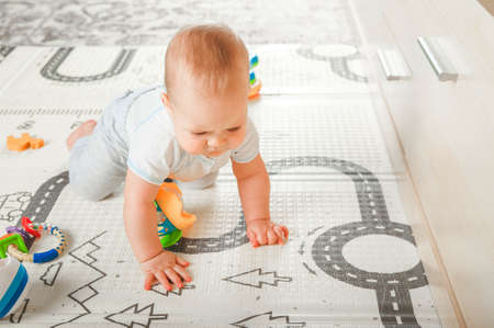 Baby plays on floor with educational toys, rattles and teething toys. Crawling babies at 8 months.の写真素材