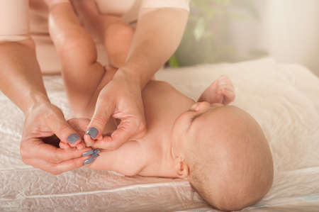 Newborn baby and mother's hands close up and copy space. Child 5 months old massage, colic, teething.の写真素材