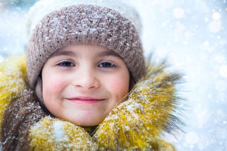 Happy girl in yellow jacket plays with snow. Children games in winter.の写真素材