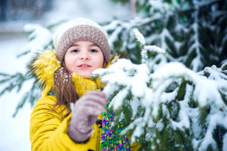 Happy girl in yellow jacket plays with snow. Children games in winter..の写真素材