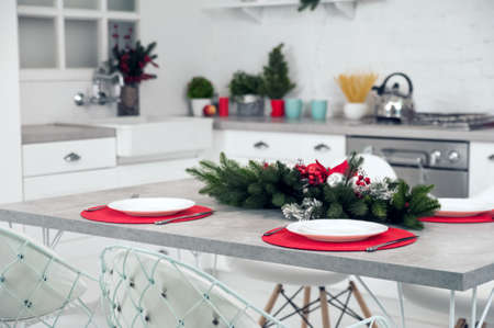 Empty plates with cutlery on red napkins close-up. Table decor for Christmas, New Year. Christmas garland with red balls on table..の写真素材