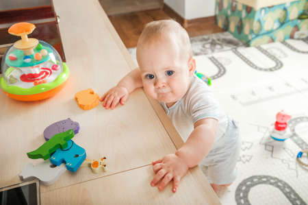 Baby plays on floor with educational toys, rattles and teething toys. Crawling babies at 8 months.